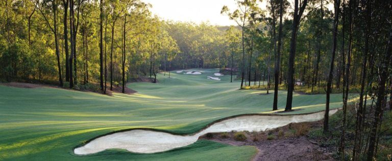 Fairway descends to green through dense forest