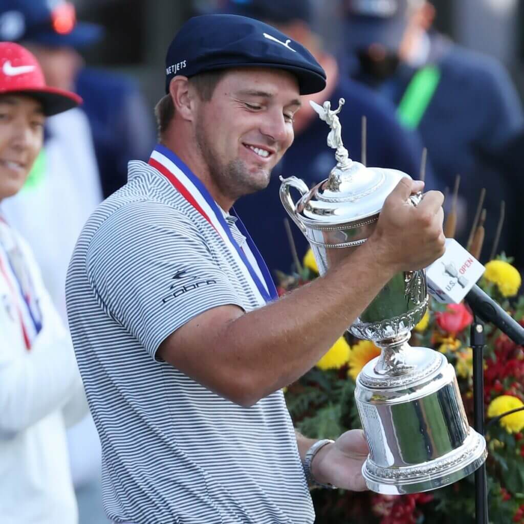 Golfer holding the US Open trophy with a winner's medal around his neck