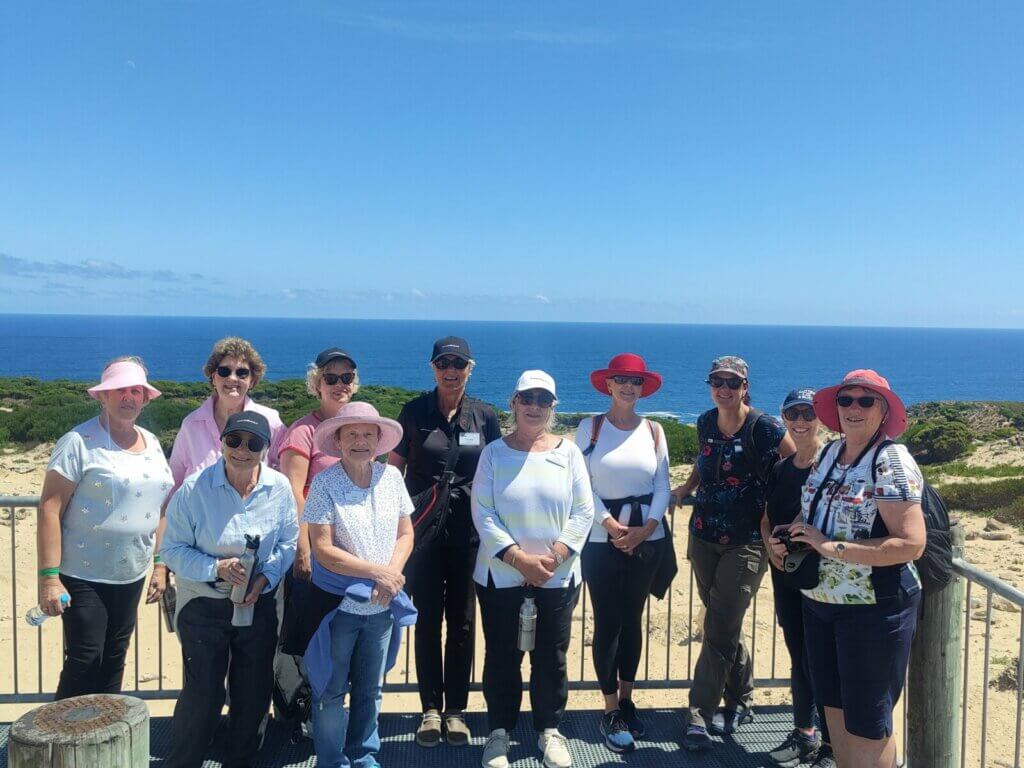 Group of women golfers posing at a coastal lookout on King Island, Tasmania, with the ocean behind