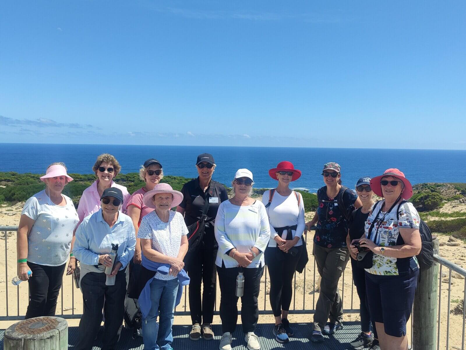 Group of women golfers posing at a coastal lookout on King Island, Tasmania, with the ocean behind