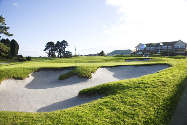 Image displaying the 18th green in the foreground at Titirangi Golf Clubhouse in the background
