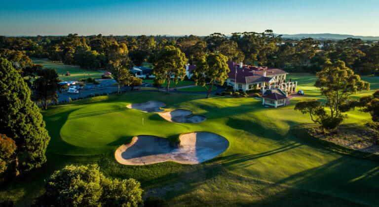 The setting sun casts long shadows over the clubhouse, car park and golf facilities at Commonwealth Golf Club, Melbourne