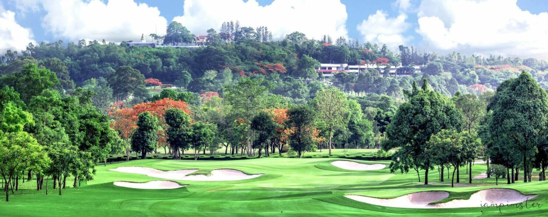 Parkland fairway and bunkers with flame trees and a hilltop temple behind at the Old Course, Siam Country Club, Thailand